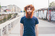© Connect Images - Close up portrait of young male hipster with red hair and beard standing on bridge