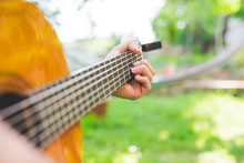 Man's Hands Playing Acoustic Guitar In Garden