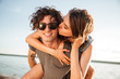 © Drobot Dean - Man giving piggyback ride to girlfriend by the ocean