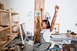 © Connect Images - Woman at desk wearing apron arms raised smiling