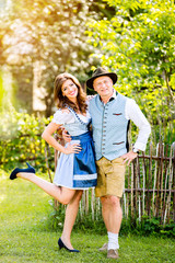 Wall Mural - Couple in traditional bavarian clothes standing in the garden