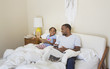 © Hello Lovely/Blend Images - African American father and daughter sitting on bed