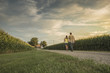 © John Fedele/Blend Images - Caucasian father and daughter walking on dirt path by corn field