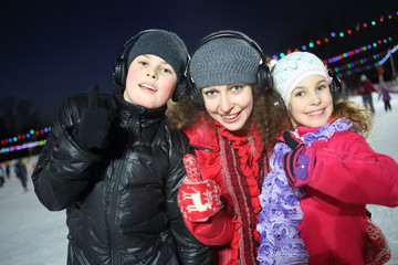 Happy mother with son and daughter make excellent gesture on the silent disco skating