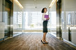 © Peathegee Inc/Blend Images - Mixed race businesswoman waiting for elevator in lobby