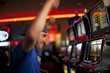 © Eric Raptosh Photography/Blend Images - Cheering Native American man playing slot machines in casino