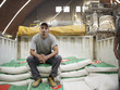 © Granger Wootz/Blend Images - Hispanic worker sitting on bag in factory