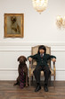 © Eric Raptosh Photography/Blend Images - Vietnamese boy sitting on elegant chair next to dog with necktie