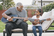 © Hello Lovely/Blend Images - African American grandfather teaching granddaughter to play guitar