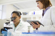 © Resolution Productions/Blend Images - Scientists using digital tablet and microscope in laboratory