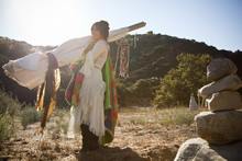 Hispanic Woman Carrying Teepee In Desert