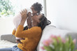 © JGI/Tom Grill/Blend Images - Black woman kissing nose of baby daughter on sofa