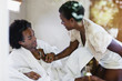 © Eric Raptosh Photography/Blend Images - African American woman kneeling on bed with husband