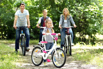 Canvas Print - Cute girl with family on bike ride in park