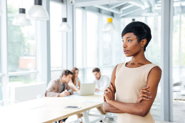 Poster - Pensive businesswoman standing with arms crossed and thinking in office