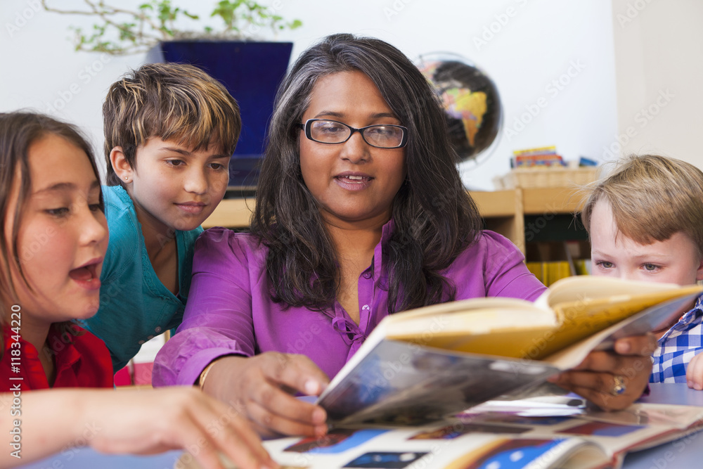 Teacher reading book to students in classroom Stock Photo | Adobe Stock