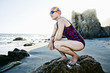 © Peathegee Inc/Blend Images - Older Caucasian woman crouching on rock on beach