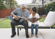 © Hello Lovely/Blend Images - African American grandfather teaching granddaughter to play guitar