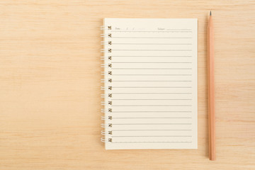 Top view of open spiral line paper notebook and brown pencil on