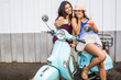 © Adam Hester/Blend Images - Pacific Islander women taking cell phone photograph on scooter