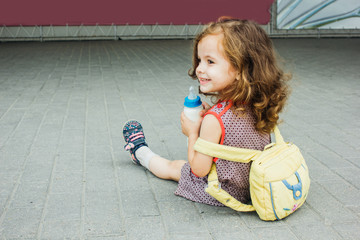 little girl with backpack and baby bottle travel in the airport or railway station, kids travel