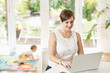 © PBNJ Productions/Blend Images - Caucasian mother using laptop at counter