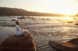 © John Henley/Blend Images - Woman practicing yoga on rock near ocean