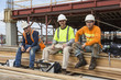 © Don Mason/Blend Images - Portrait of smiling workers sitting at construction site