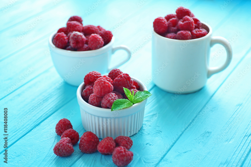 Fresh raspberry in cups on table