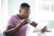 © Resolution Productions/Blend Images - Black man drinking coffee using digital tablet