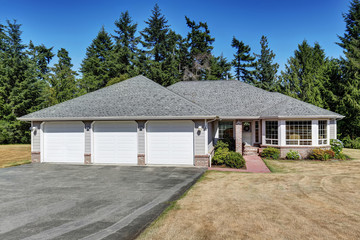 American one level house exterior with three garages and tile walkway.