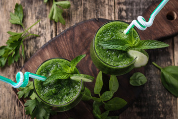 Fresh green smoothie with straws on a wooden table,healthy vegan food