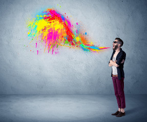 Hipster guy shouting colorful paint on wall