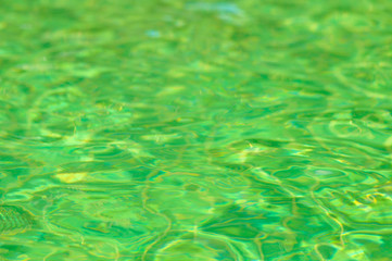emerald green water surface with sun reflection in swimming pool