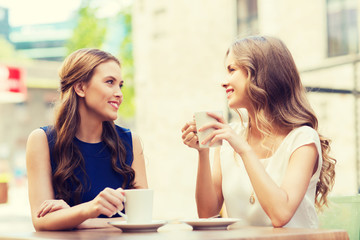 Canvas Print - young women drinking coffee and talking at cafe