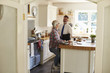 © Guerilla - Gay couple in kitchen, one leaving for work, full length