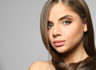 Wall Mural - Young woman with healthy hair on light background