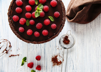 Wall Mural - Delicious chocolate tart with raspberry on a wooden background