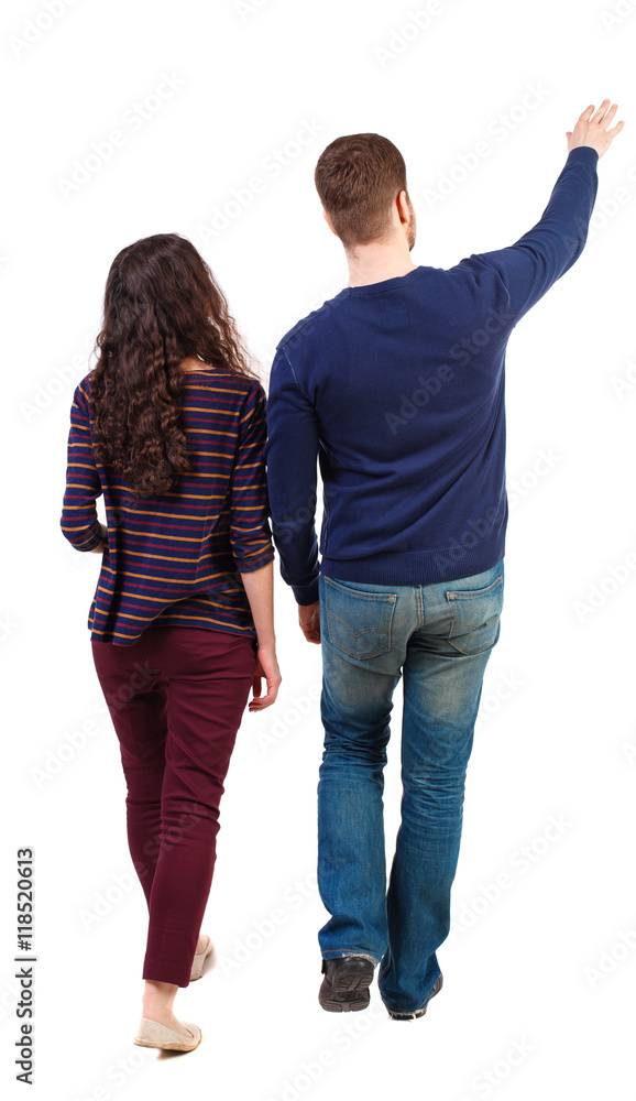 Back view of walking young couple (man and woman) pointing. Rear view ...
