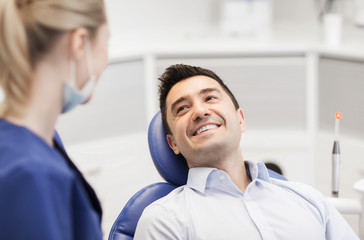 Canvas Print - female dentist with happy male patient at clinic