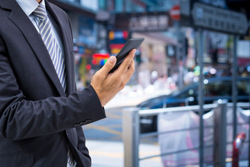 isolated business man hold the smartphone on the street 
