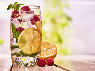 Alcohol drink. On wooden boards is glass with alcohol drink and ice cubes inside. Drink two hundred eighty nine cocktail raspberry mojito and half lwith mint. Country life. Outdoor. Light background.