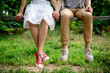 Close up of couple in keds sitting on bench.