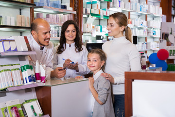 Two pharmacists helping customers