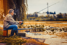 Senior Man Fishing On A Freshwater Lake Sitting Patiently 