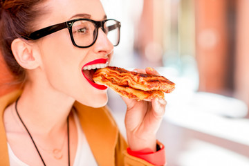 Young woman eating lasagna with bolognese outdoors on the street in Bologna city in Italy. Lasagna bolognese was invented in Bologna city. Soft focus with small depth of field