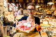 Young woman sitting near the food shop with traditional italian appetizer on the blurred food showcase background in Bologna city. Bologna is the gastronomic center of Italy