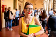 © rh2010 - Portrait of a young female student dressed casually with colorful books during the break in crowded corridor at the old university