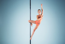The Strong And Graceful Young Girl Performing Acrobatic Exercises On Pylon