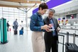 © Wavebreak Media - Business people holding boarding pass and using mobile phone